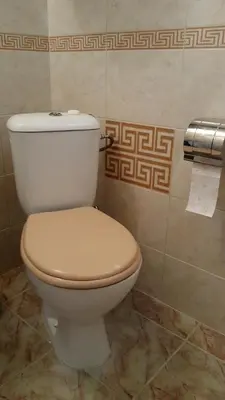 a white toilet in a bathroom with a roll of toilet paper at Happy beach in Varna City