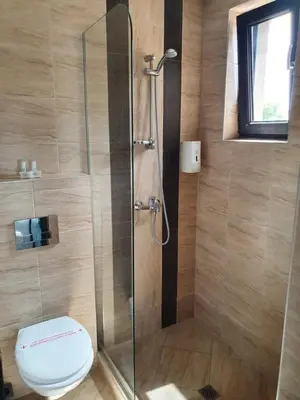 a bathroom with a toilet and a glass shower at Family Hotel Novel City in Burgas City