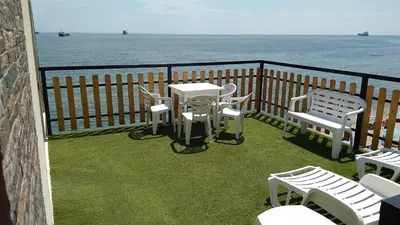 a balcony with white chairs and tables and the ocean at Hemingway rooms in Happy Beach in Varna City