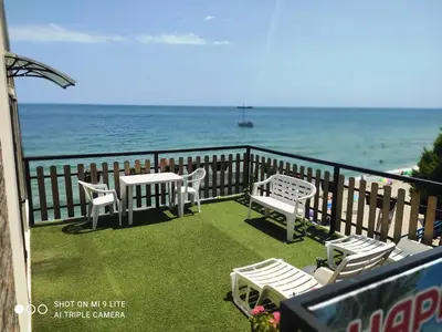 a balcony with chairs and tables and the ocean at Hemingway rooms in Happy Beach in Varna City