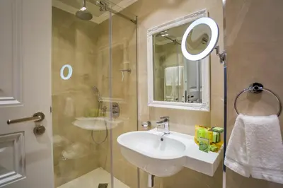a bathroom with a sink and a shower with a mirror at Hotel Residence Promenade in Burgas City