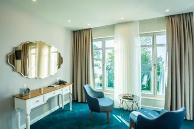 a hotel room with a vanity and chairs and a mirror at Hotel Residence Promenade in Burgas City