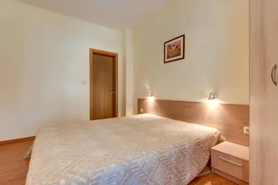 a bedroom with a large bed with a wooden headboard at ДриймБг Апартаменти - Райска Градина, Свети Влас in Sveti Vlas