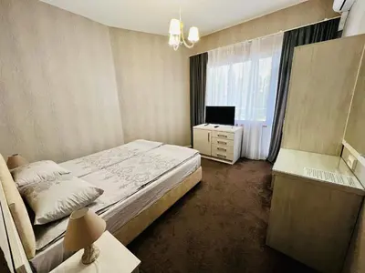 a bedroom with a bed and a desk and a television at Джорджия in Kiten