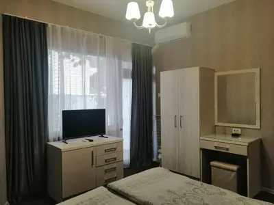 a bedroom with a bed and a desk and a television at Джорджия in Kiten