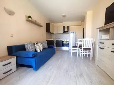 a living room with a blue couch and a kitchen at Aпартаменти Хоризонт in Sozopol