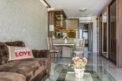 a living room with a couch and a table with flowers at Apartcomplex Golden Bay in Ravda