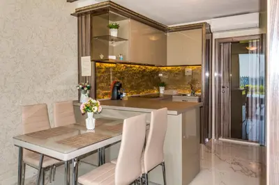 a kitchen with a table and white chairs at Apartcomplex Golden Bay in Ravda