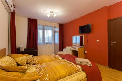 a bedroom with orange walls and a bed and a television at Holiday Home Paulovnia in Tschenge