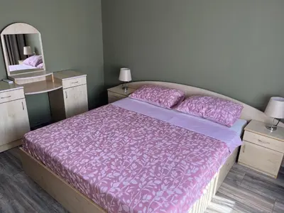 a bedroom with a large bed with pink sheets and a mirror at Одеса 37 in Sozopol