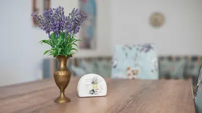 a vase with purple flowers and a plate on a table at Lora boutique in Pomorie