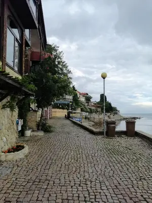 a cobblestone street next to a building and the ocean at Apartament ,,EDELVAIS- LUX'' in Nesebar