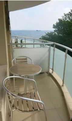 a table and chair on a balcony with the ocean at Family Hotel Albizia Beach in Varna City