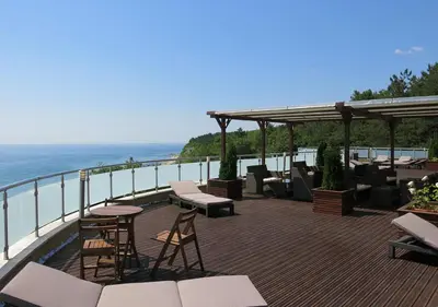 a deck with chairs and tables and a view of the ocean at Family Hotel Albizia Beach in Varna City