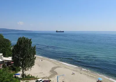 a boat in the ocean next to a beach at Family Hotel Albizia Beach in Varna City