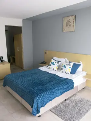 a bedroom with a large bed with a blue blanket at Family Hotel Albizia Beach in Varna City