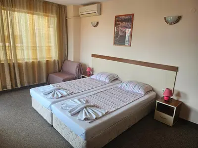 a hotel room with two beds and a chair at Hotel Orchidea in Sozopol