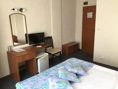 a bedroom with a bed and a desk and a mirror at Family Hotel Lazuren Briag in Burgas City