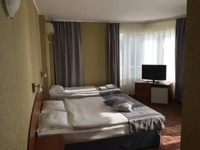a hotel room with two beds and a television at Family Hotel Lazuren Briag in Burgas City
