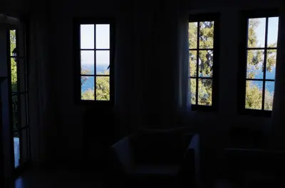 a dark room with three windows and a chair at Beautiful 1st-Line Seaview Private Appartement in The Cliff resort in Obzor