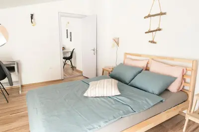 a bedroom with a bed with blue sheets and pink pillows at Balabanov White in Varna City