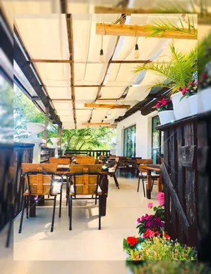 a restaurant with wooden tables and chairs and plants at Villa Adrian in Shkorpilovtsi