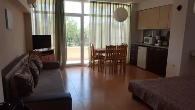 a living room with a couch and a kitchen with a table at Grand Kameliq in Sunny Beach