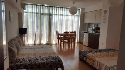 a living room with a couch and a table and a kitchen at Grand Kameliq in Sunny Beach