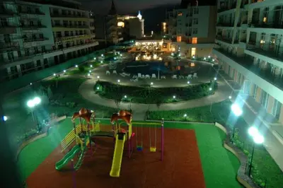 a park with a roller coaster and a playground at night at Grand Kameliq in Sunny Beach