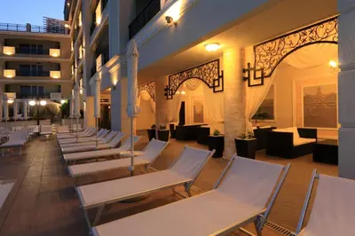 a row of white lounge chairs in a building at Penelopa Palace Apart Hotel & SPA in Pomorie