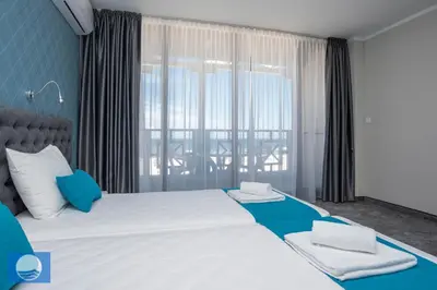 a bedroom with a large white bed with blue accents at Oasis Del Sol - Front Beach in Lozenets