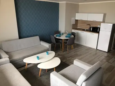 a living room with a couch and tables and a kitchen at Oasis Del Sol - Front Beach in Lozenets