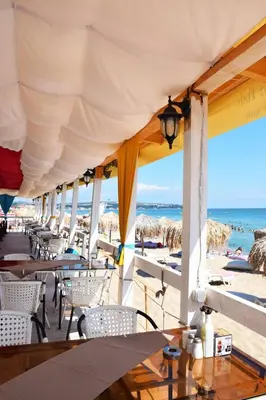 a restaurant on the beach with tables and chairs at Alice Apartment in Obzor