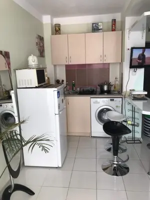 a kitchen with white appliances and a stool in it at Alice Apartment in Obzor