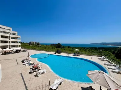 a large swimming pool with chairs and umbrellas at Апартаменти Сънбрийз - Sunbreeze Apartments in Byala