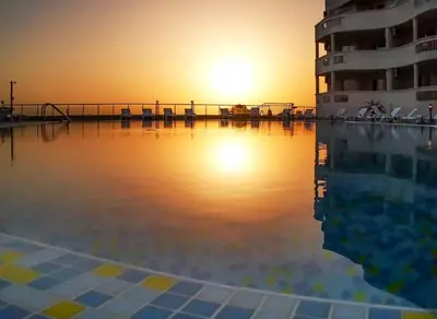 a hotel swimming pool with the sunset in the background at Апартаменти Сънбрийз - Sunbreeze Apartments in Byala