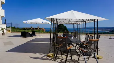 a table and chairs under an umbrella on a patio at Апартаменти Сънбрийз - Sunbreeze Apartments in Byala