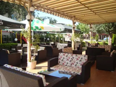 a patio with chairs and tables and an umbrella at Hotel Astra in Ravda
