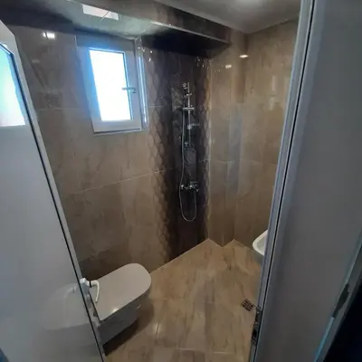 a bathroom with a toilet and a shower with a window at Gradina in Chernomorets