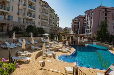a pool with chairs and umbrellas next to some buildings at Sunny Beach Hills - Menada Apartments in Sunny Beach