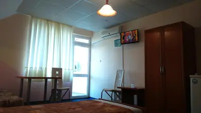 a bedroom with a bed and a window and a table at Familia Fantastiko in Kiten