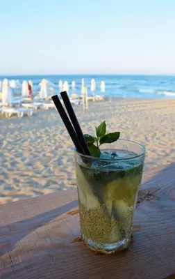 a drink sitting on a table at the beach at Helga Apartment in Obzor