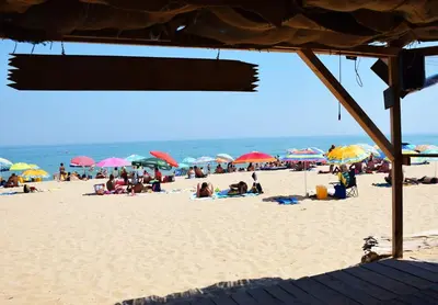 a group of people on a beach with umbrellas at Helga Apartment in Obzor