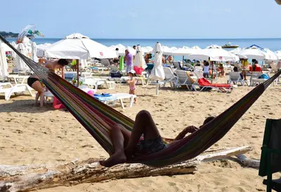 a person laying in a hammock on a beach at Helga Apartment in Obzor