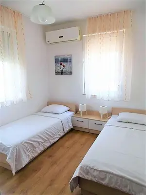 two beds in a room with white walls and wooden floors at Apartment Lozenets in Lozenets