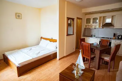 a bedroom with a bed and a table and a kitchen at Apartment Garden of Eden in Sveti Vlas