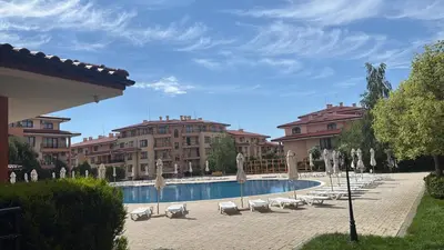 a swimming pool with chairs and umbrellas and buildings at Star Dreams, Sveti Vlas in Sveti Vlas
