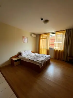 a bedroom with a bed in a room with wooden floors at Mario Beach Apartment Nessebar in Nesebar