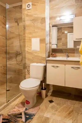 a bathroom with a toilet and a shower and a sink at Apartment EliMar in Burgas City