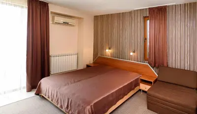a hotel room with a bed and a chair at Guest House Ianis Paradise in Nesebar